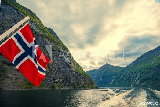 Picture of Mountain landscape with cloudy sky Majestic Geiranger fjord View from ship Norvegian flag against beautiful nature of Norway